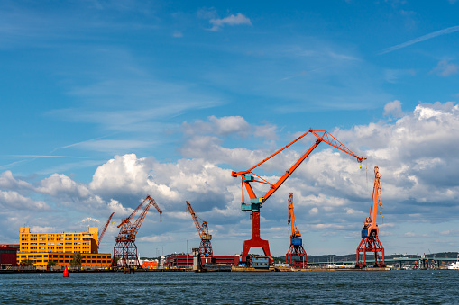 Summer seascape view of harbor cranes and dock against blue cloudy sky in Gothenburg Sweden. Horizontal composition.
