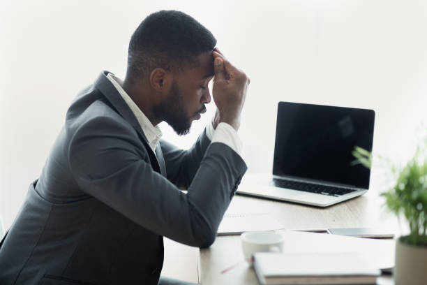 istock Stressed african businessman sitting in office with hand on forehead 1167728485