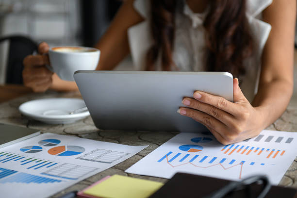 istock Female executive drink coffee and use tablet during break.She sat by the window in the office.Data graph placed on the desk. 1167730770