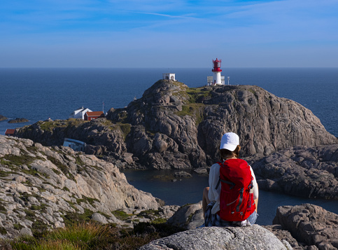 girl with red backpack doing walking on the lighthouse of Lindesnes, Norway