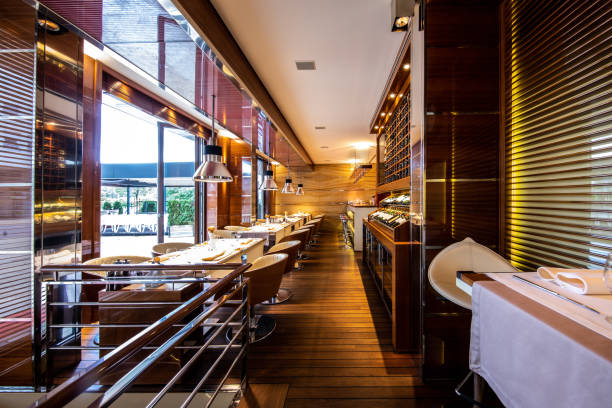 A row of dining tables located next to a wine display shelf in a high profile restaurant interior
