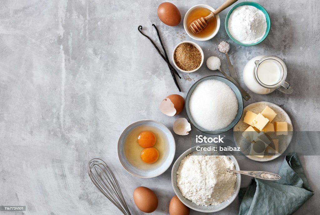 Baking ingredients: flour, eggs, sugar, butter, milk and spices Baking ingredients: flour, eggs, sugar, butter, milk and spices on gray marble background. Top view. Space for text Baking Stock Photo