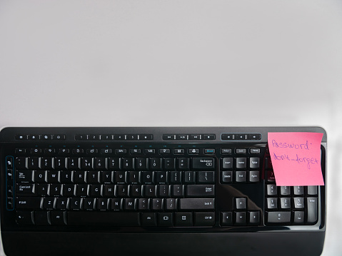 Pink sticky note with  password  don't forget on computer keyboard .  The scene is situated in a studio environment. The picture is taken with Panasonic GH5 camera.