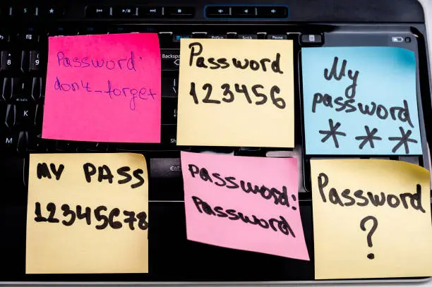 Photo of Sticky notes with weak  passwords and part of keyboard