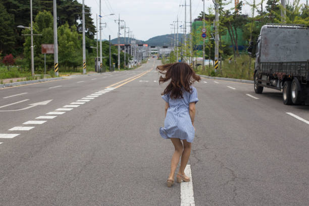 istock Back view of woman standing on road 1167736839