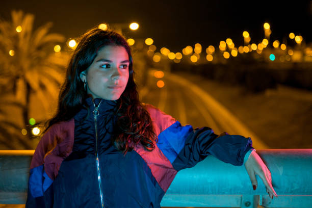 Cool teenager girl on a bridge over highway in Barcelona at night stock photo