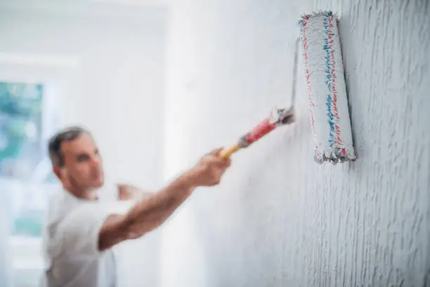 Photo of Painter man at work with a paint roller