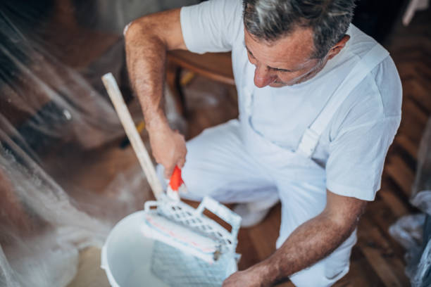 painter man at work with a paint roller and ladder - brushing human hand paintbrush artist imagens e fotografias de stock