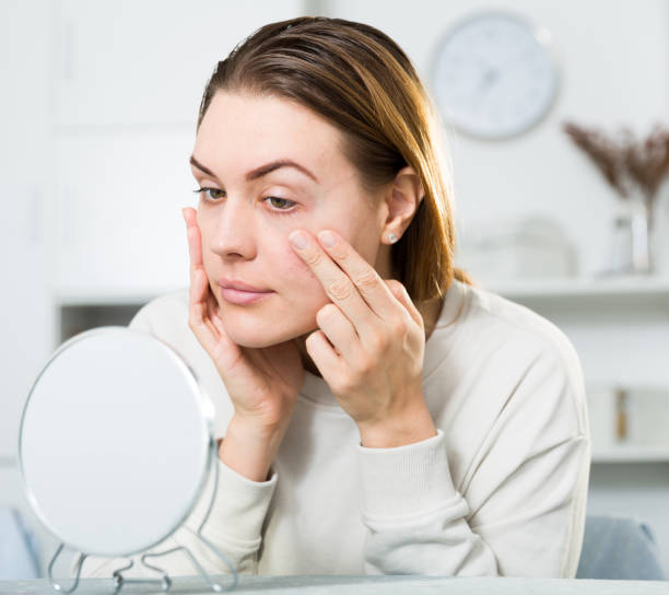 istock Cheerful woman is concentrared looking on her face in the mirror 1167741853