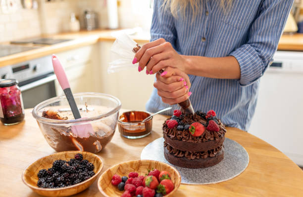 istock Using a piping bag to pipe chocolate icing on to a cake 1167742608