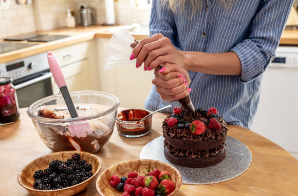 istock Using a piping bag to pipe chocolate icing on to a cake 1167743873