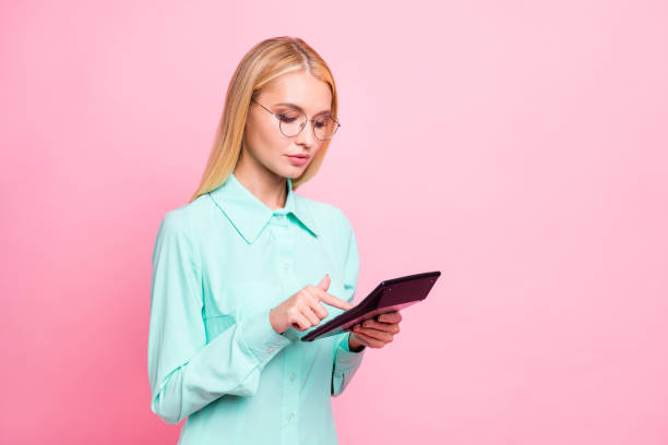 istock Turned portrait of concentrated lady using calculator count statistics wearing mint color shirt eyeglasses eyewear isolated over pink background 1167743922