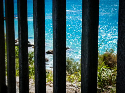 A beautiful ocean sparkles behind bars, symbolizing being trapped or imprisoned