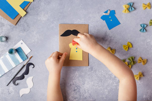 Making greeting card for Fathers Day. Shirt with butterfly from pasta. Card from paper. moustache. Childrens art project stock photo