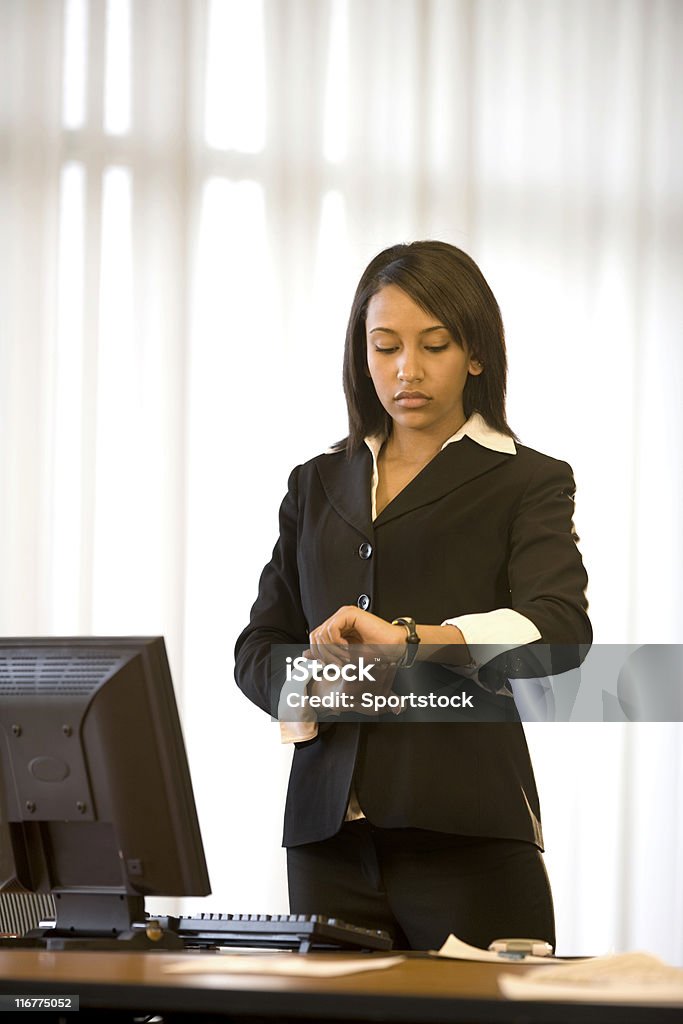 Beautiful Woman In Her Office Pretty african american businesswoman checking her watch in her office. African Ethnicity Stock Photo
