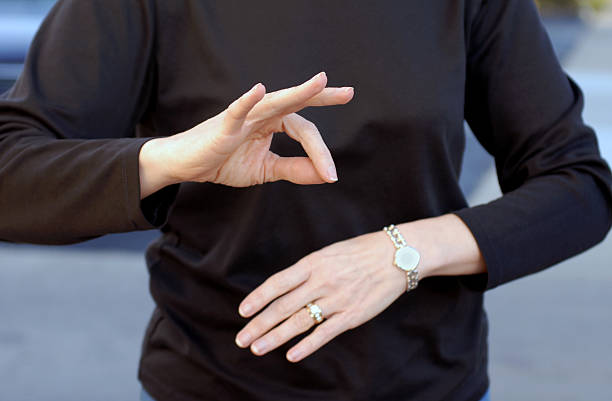 A woman using sign language wearing a black shirt Sign language for "French"; or "okay" hand signal. american sign language photos stock pictures, royalty-free photos & images