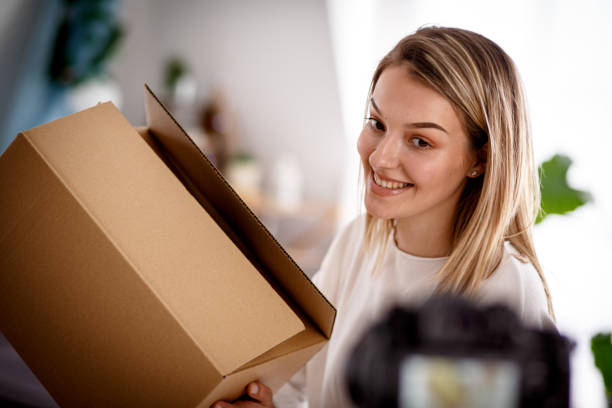 istock Smiling female vlogger showing off a box to camera while filming a video 1167753155