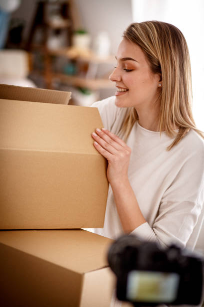 istock Confident young female blogger doing a live stream while opening boxes for her audience 1167753183
