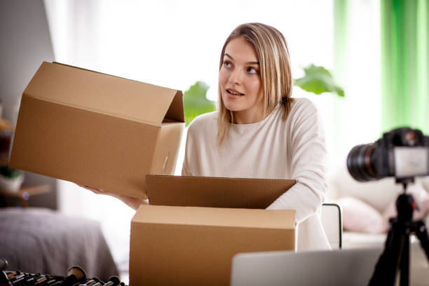 istock Smiling young female influencer opening boxes of mail on camera 1167753187