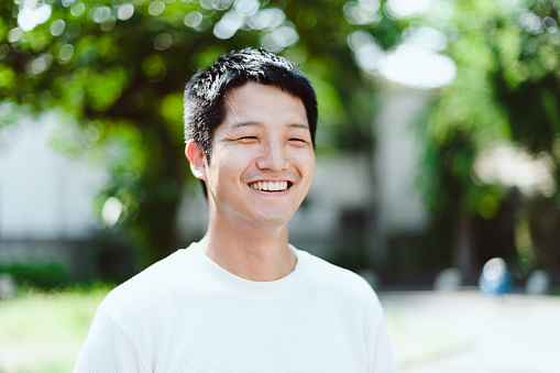 An interview-style portrait of a young Japanese man outdoors on a sunny day.