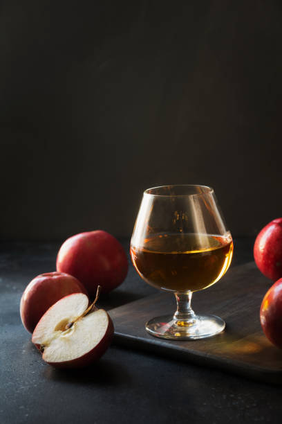 Glass with Calvados brandy and red apples on black. Glass with Calvados brandy and red apples on black. Close up. glass of bourbon stock pictures, royalty-free photos & images