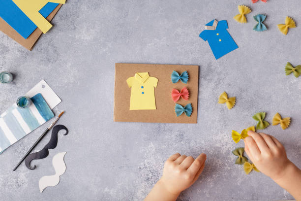 Making greeting card for Fathers Day. Shirt with butterfly from pasta. Card from paper. moustache. Childrens art project stock photo