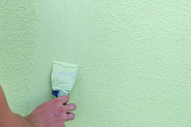 istock Contractor worker hand without one finger holding spatula for plaster and applying to wet concrete pinted in green. Disability of worker concept. 1167755012