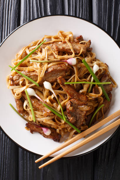 istock Beef Chow Fun - Beef stir-fried with rice noodle, bean sprouts, spring onions and Chinese chives is a famous Cantonese dish closeup on the plate. Vertical top view 1167757767