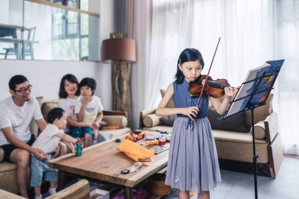 niña tocando el violín frente a los miembros de la familia - violin family fotografías e imágenes de stock