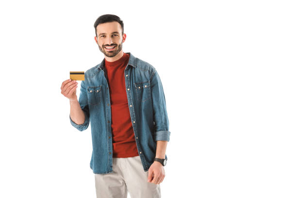 smiling man holding credit card while looking at camera isolated on white