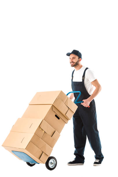 istock cheerful handsome delivery man transporting cardboard boxes loaded on hand truck isolated on white 1167768302