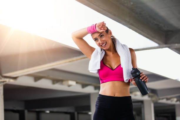 istock Young smiling female resting after an active fitness training while standing against gray wall with copy space area for your text message, satisfied fit woman resting after an active fitness training 1167768545