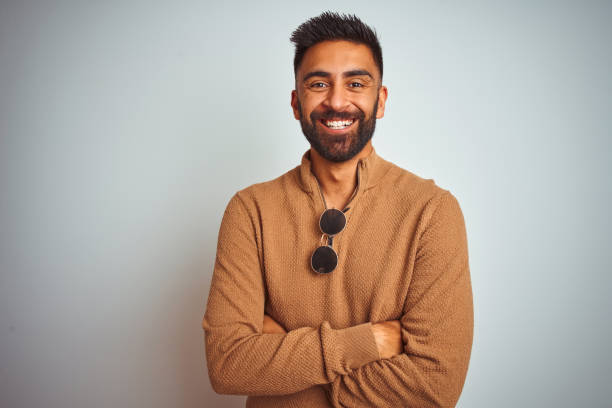 istock Indian man wearing elegant sweater and sunglasses standing over isolated white background happy face smiling with crossed arms looking at the camera. Positive person. 1167768961