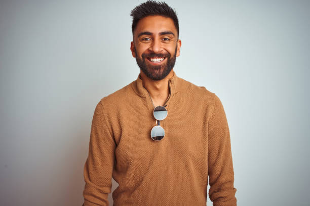istock Indian man wearing elegant sweater and sunglasses standing over isolated white background with a happy and cool smile on face. Lucky person. 1167769016