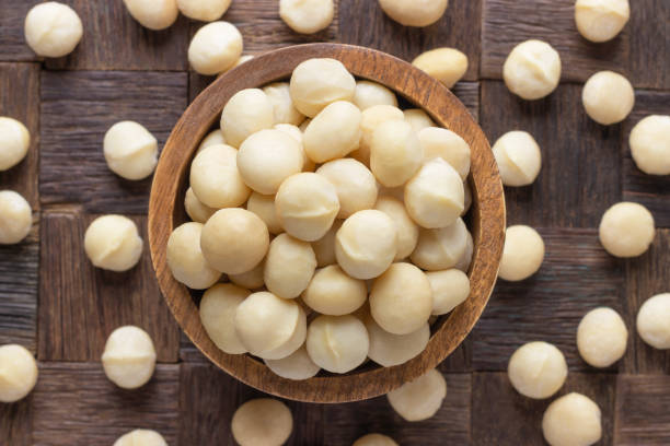 istock macadamia nuts peeled in wooden bowl, top view. 1167770572