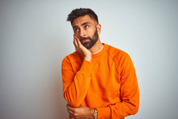 istock Young indian man wearing orange sweater over isolated white background thinking looking tired and bored with depression problems with crossed arms. 1167770734