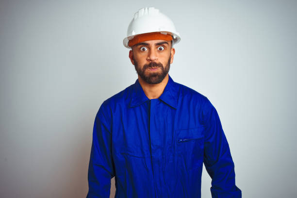 istock Handsome indian worker man wearing uniform and helmet over isolated white background puffing cheeks with funny face. Mouth inflated with air, crazy expression. 1167770744