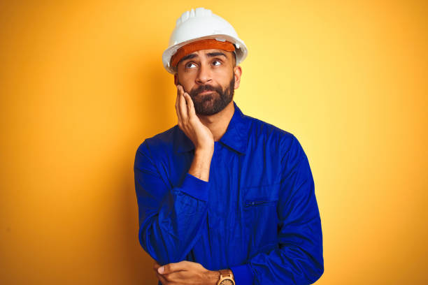 istock Handsome indian worker man wearing uniform and helmet over isolated yellow background thinking looking tired and bored with depression problems with crossed arms. 1167770757