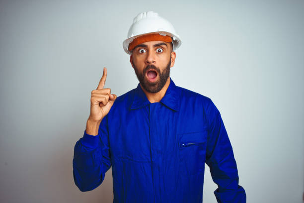 istock Handsome indian worker man wearing uniform and helmet over isolated white background pointing finger up with successful idea. Exited and happy. Number one. 1167770781