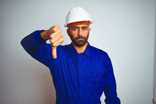 istock Handsome indian worker man wearing uniform and helmet over isolated white background looking unhappy and angry showing rejection and negative with thumbs down gesture. Bad expression. 1167770782
