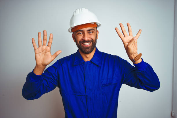 istock Handsome indian worker man wearing uniform and helmet over isolated white background showing and pointing up with fingers number nine while smiling confident and happy. 1167770784