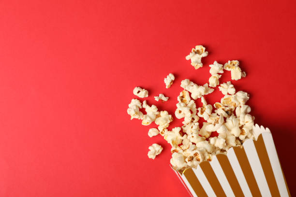 istock Flat lay composition with striped box and popcorn on color background 1167770892