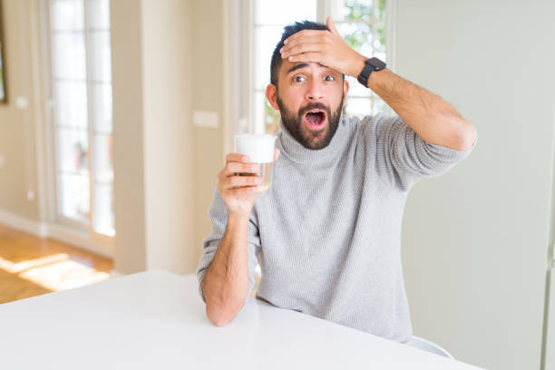 istock Handsome hispanic man drinking a cup of coffee stressed with hand on head, shocked with shame and surprise face, angry and frustrated. Fear and upset for mistake. 1167772896