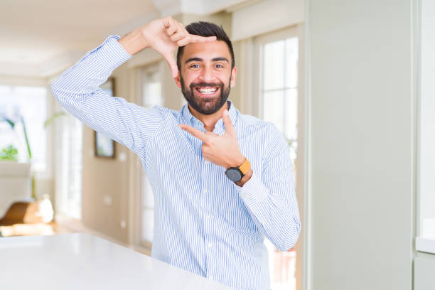 istock Handsome hispanic business man smiling making frame with hands and fingers with happy face. Creativity and photography concept. 1167773311
