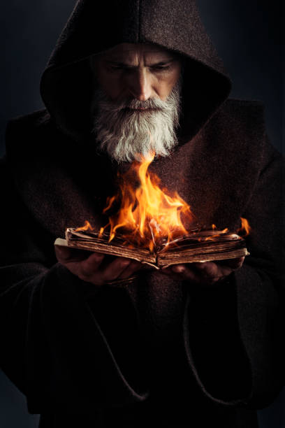 Senior monk wearing traditional clothes book in fire Portrait of senior monk holding burning book merlin the wizard stock pictures, royalty-free photos & images
