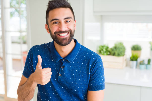 istock Handsome hispanic man at home doing happy thumbs up gesture with hand. Approving expression looking at the camera with showing success. 1167774494