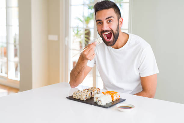 istock Handsome man smiling happy enjoying eating fresh colorful asian sushi using chopsticks 1167774826