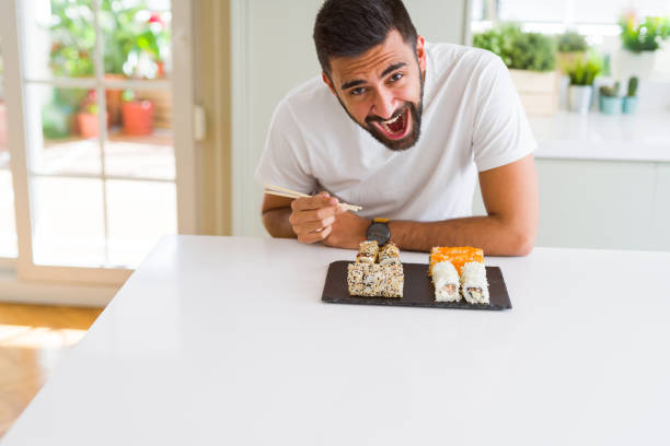 istock Handsome man smiling happy enjoying eating fresh colorful asian sushi using chopsticks 1167774828