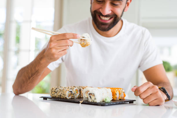 istock Handsome man smiling happy enjoying eating fresh colorful asian sushi using chopsticks 1167774857