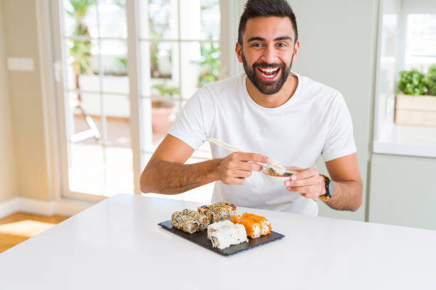 istock Handsome man smiling happy enjoying eating fresh colorful asian sushi using chopsticks 1167774930